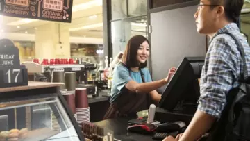 Une vendeuse dans un café prend la commande d'un client